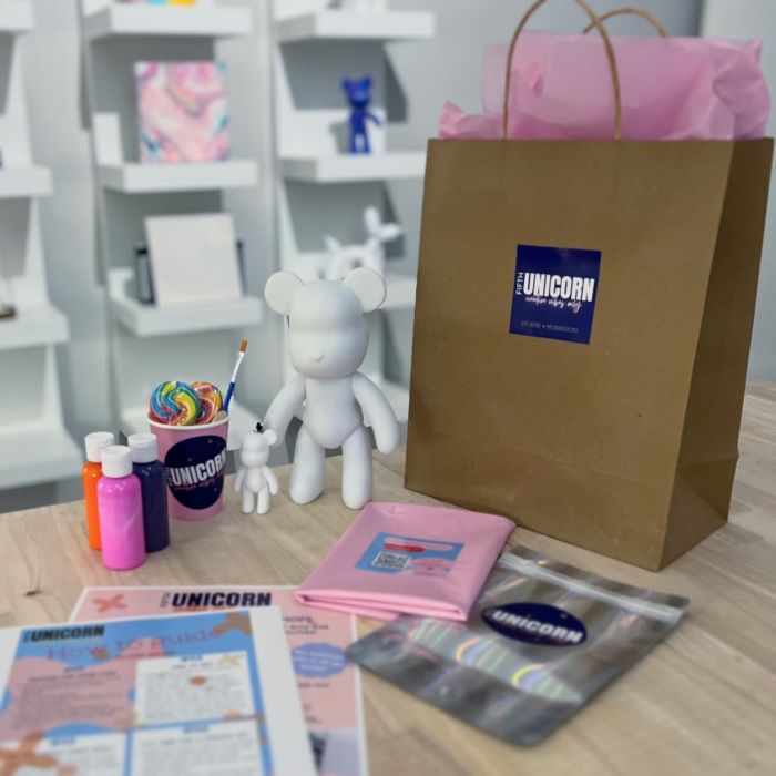 Fluid-Bear-DIY-Kit-Order Fluid Bear Art Kit with blank medium and keychain bear, pink, orange and purple fluid paints and paperbag with instructions and materials. Background is Fifth Unicorn studio in Newport, North Brisbane